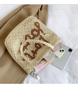 Spacious beige woven tote bag with brown embroidery shown with personal items for scale