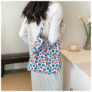 Detail shot of a large floral canvas tote bag with vibrant patterns on white dress model