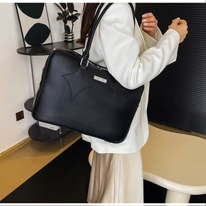 Detail of minimalist black PU leather tote bag with star stitching and metallic logo