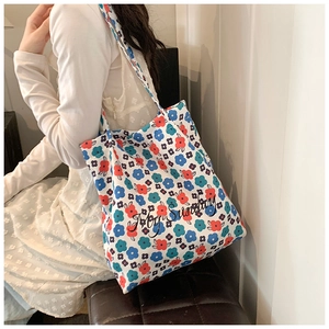 Detail of white canvas tote bag with floral pattern and My Sunday print on shoulder