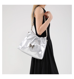 Detail of silver metallic PU bag featuring 3D butterfly ornament and drawstring