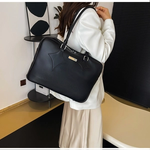 Detailed side view of a large black PU leather tote bag with star stitching on shoulder