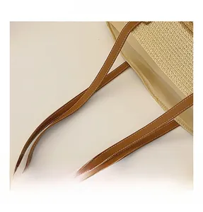 Close-up of woven fabric handbag featuring brown leather handles with white stitching detail