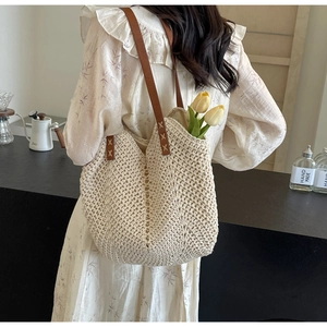 Detail of hand-woven off-white tote bag with brown leather straps and X-shaped stitching