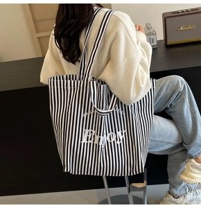 Vertical black and white striped canvas tote bag with white Enjoy print on shoulder