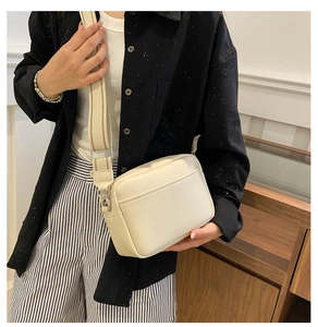 Side view of cream square PU leather crossbody bag with wide striped canvas strap