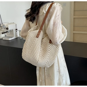 Close-up of beige woven tote bag with brown leather straps and intricate V-stitch texture