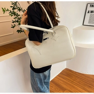 Macro detail of the creamy white PU leather tote showing star patches and metal logo plate
