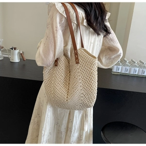 Detailed shot of bohemian woven tote bag featuring brown leather straps and cross stitching