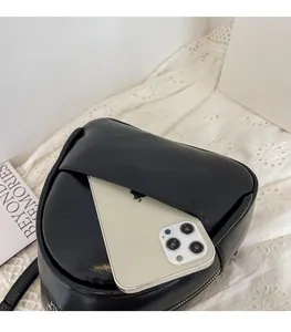 Detail view of small black PU leather backpack showing front pocket for phone storage
