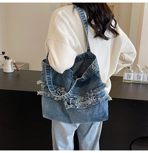 Détail du sac cabas en denim avec texte Sweet Home blanc et bordure à franges effilées