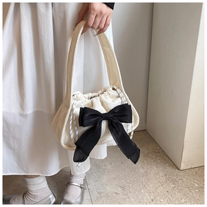 Close-up of cream corduroy drawstring handbag featuring a large black decorative bow