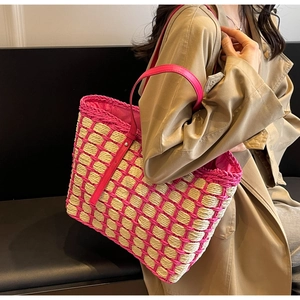 Détail du sac cabas en paille tressée avec anse en cuir rose sur l'épaule du mannequin