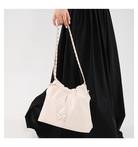 Close-up of cream pleated leather crossbody bag with golden butterfly buckle and chain