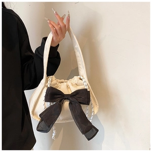 Close-up of white corduroy handbag with large black organza bow and drawstring detail