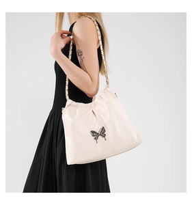 Close-up of beige PU leather crossbody bag featuring a decorative butterfly metal buckle