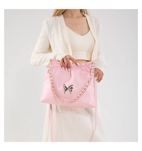 Detail of light pink PU leather crossbody bag with silver butterfly and gold chain strap
