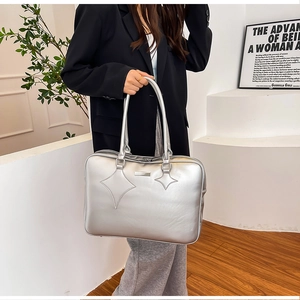 Detail of silver metallic PU handbag featuring star-quilted stitching and sleek handles
