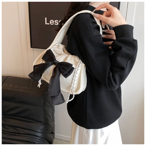 Detail of off-white corduroy shoulder bag with large black bow and drawstring closure