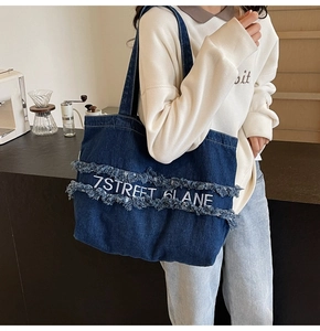 Détail du sac fourre-tout en denim bleu avec bords effilochés et logo imprimé