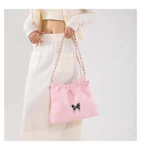 Detail of pink PU leather shoulder bag with metallic butterfly and gold chain strap