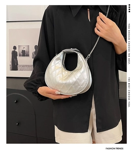 Sac demi-lune argenté avec chaîne métallique porté sur une chemise noire élégante