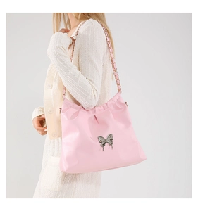 Close-up of pink shoulder bag featuring pleated details and a silver butterfly buckle