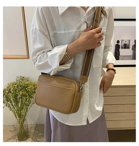Brown PU leather crossbody bag with wide fabric strap and silver metal hooks shown on model
