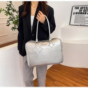 Silver PU leather tote bag with star stitching detail held by model in casual suit