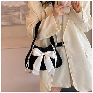 Detail of black corduroy handbag with a large cream satin bow and rope drawstrings