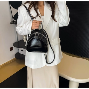 Detailed close-up of a minimalist black PU leather mini backpack with silver metal zippers