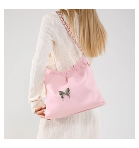 Detail of pink PU leather crossbody bag with large silver metal butterfly and chain strap