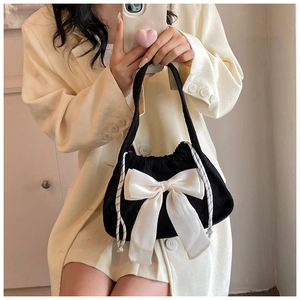 Detail view of black corduroy shoulder bag with large white satin bow and drawstring