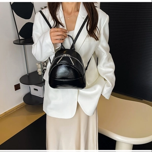 Close-up of shiny black PU leather mini backpack with silver metal zippers and handle