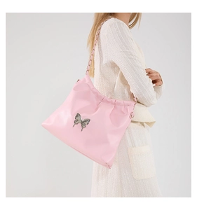 Detail of pink pleated bucket bag featuring a silver metal butterfly and chain strap