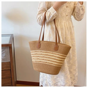 Detail of woven straw tote bag with brown leather handles worn by a woman in lace dress