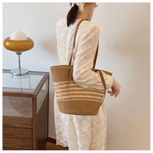 Lifestyle view of woven striped tote bag with brown leather straps on a model in white dress