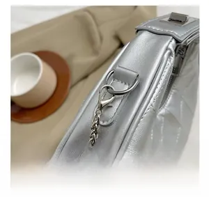 Détails d'un sac matelassé argenté montrant la chaîne en métal et le fermoir brillant