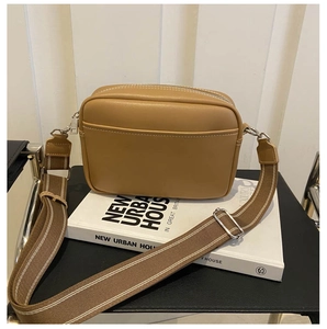 Detail view of caramel camera bag showing white stitching and silver hardware accents