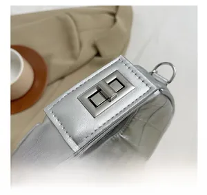 Gros plan d'un sac argenté matelassé avec un fermoir tournant en métal brillant