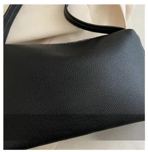 Close-up of black litchi grain PU leather texture on minimalist shoulder handbag