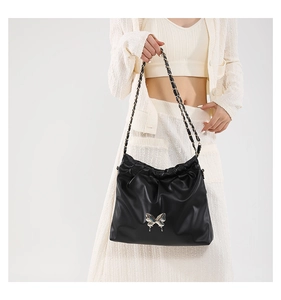 Close-up of black PU leather shoulder bag featuring a silver metal butterfly ornament