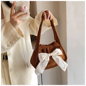 Detailed close-up of brown corduroy handbag featuring a decorative white bow accent