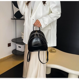Detail of a sleek black PU leather mini backpack featuring silver metal zippers and handles