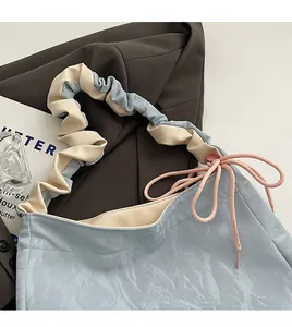 Detail of light blue PU leather crossbody bag with pleated strap and pink bow accent