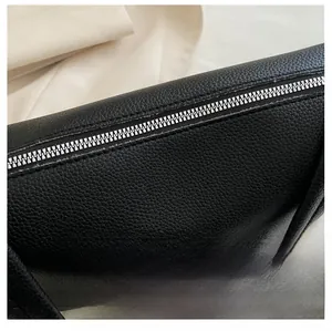 Close-up of a smooth silver metal zipper on premium black lychee pattern PU leather bag