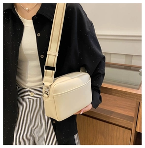 Detail view of cream white PU leather crossbody bag with striped wide fabric strap