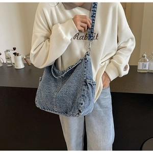 Detail van de verstelbare brede schouderband en zijvak van de gewassen denim hobo tas