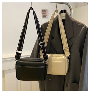 Detail of premium crossbody camera bag with wide striped strap and textured leather finish