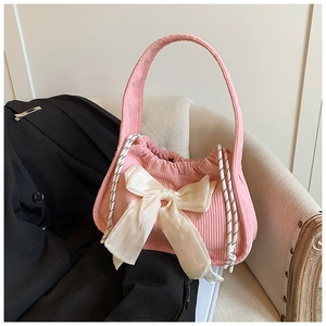 Pink corduroy handbag with large silk bow decoration and drawstring closure on a chair